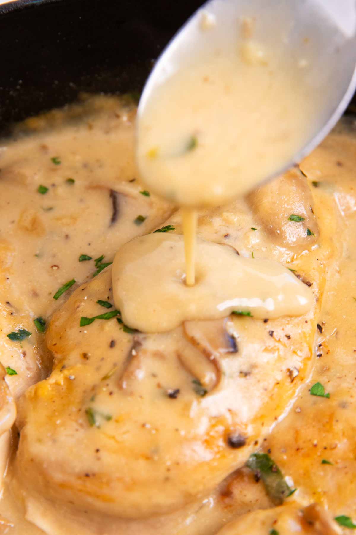 Drizzling mushroom gravy over a chicken breast.