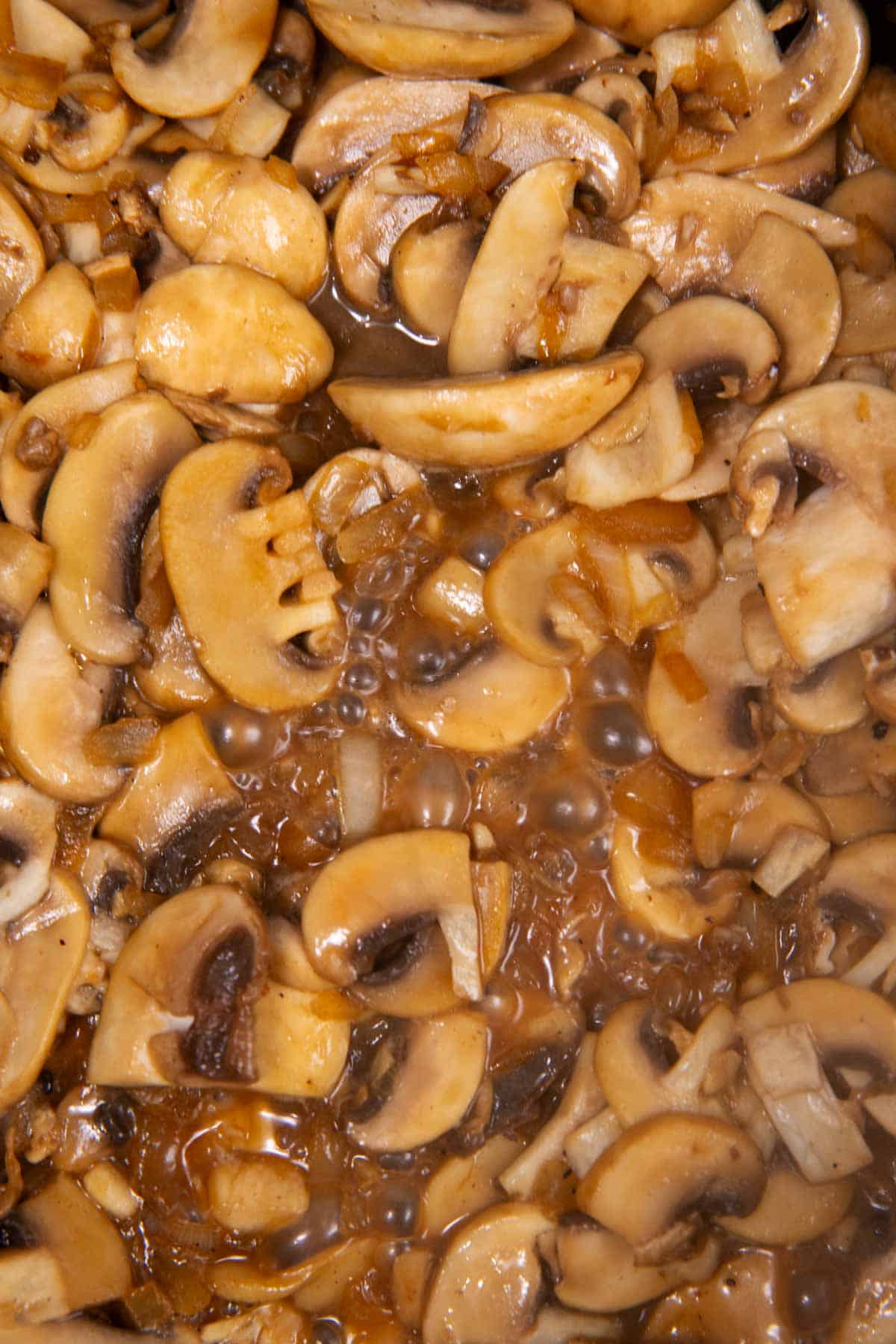 Close up of cooking mushrooms in skillet.
