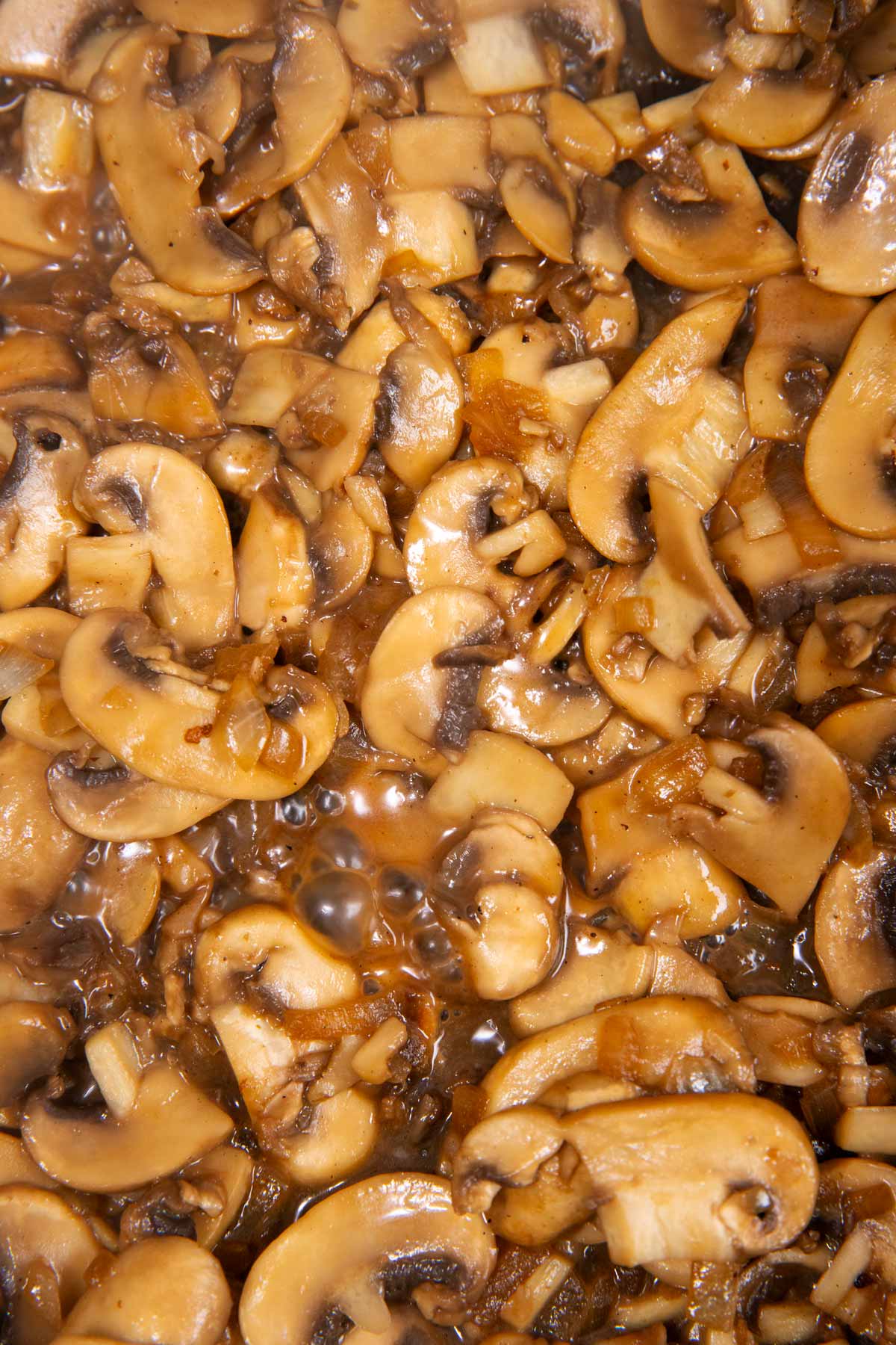 Close up of cooking mushrooms in skillet.