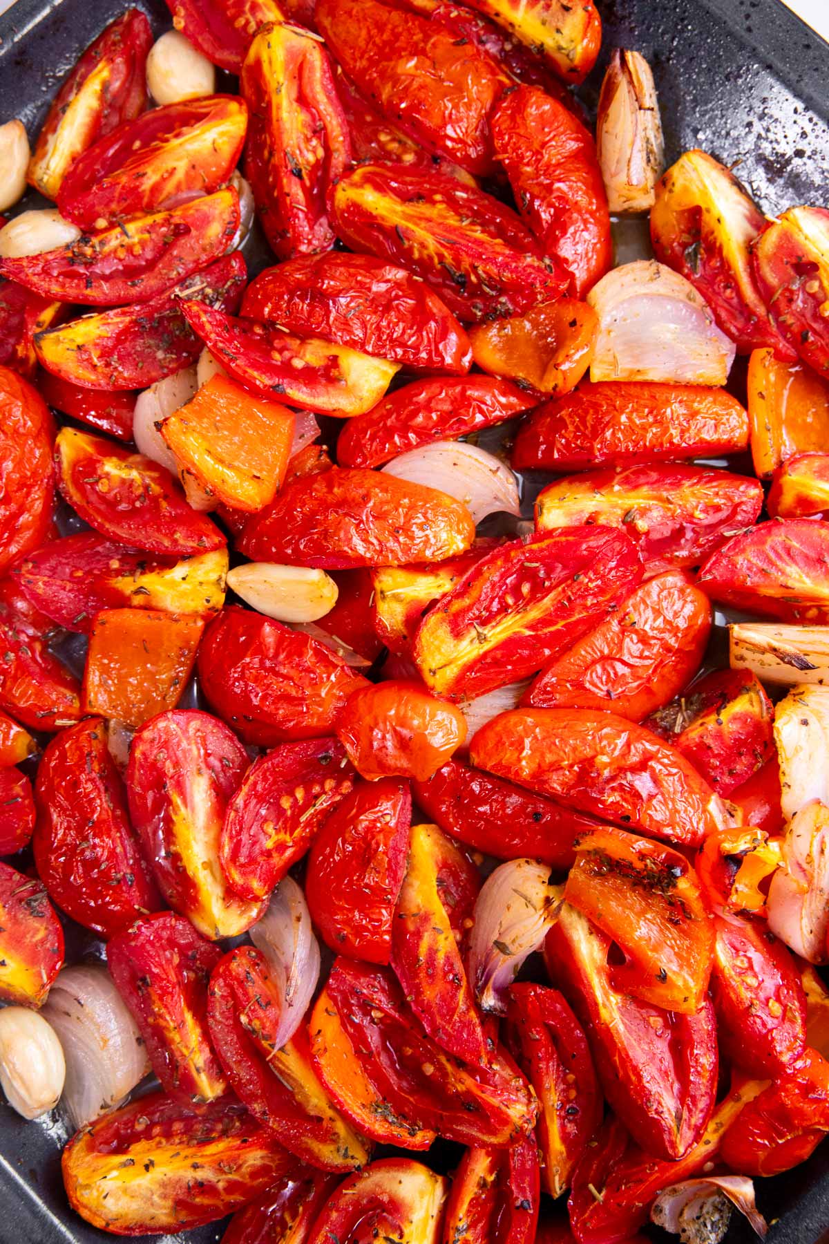 Roasted tomatoes and aromatics on a sheet pan.