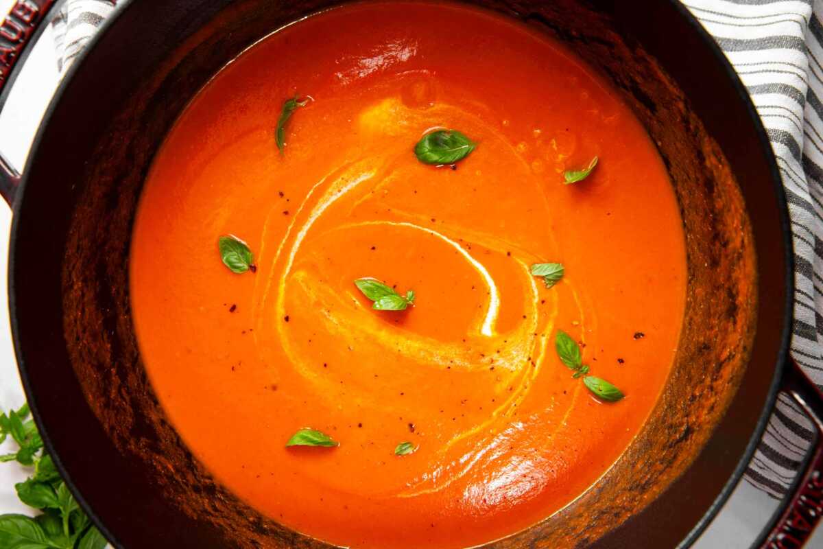Overhead view of tomato soup in a cast iron pot.