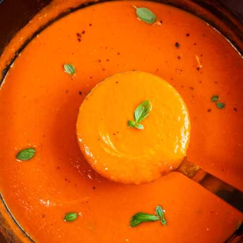 Close up photo of a ladle scooping tomato soup from a pot.
