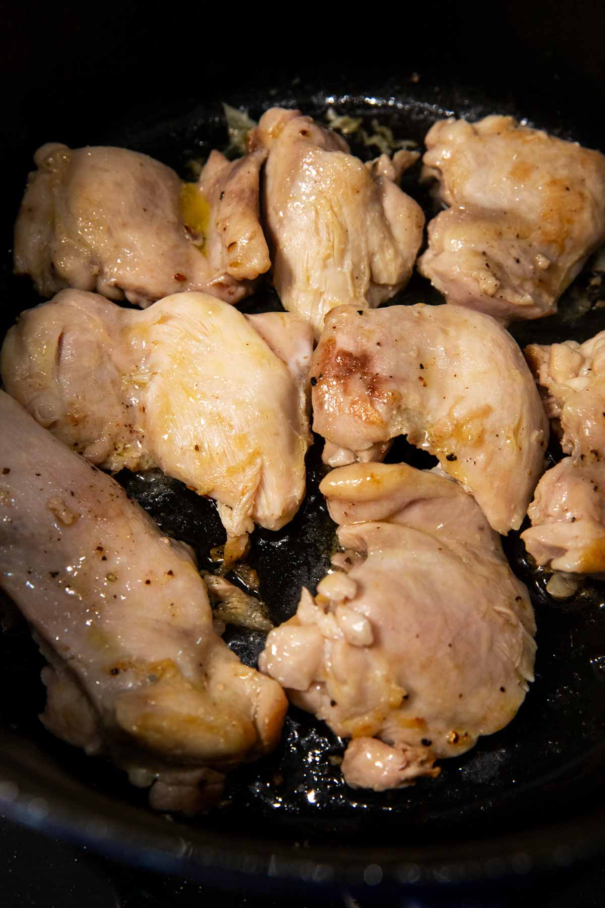 Chicken thighs searing in cast iron pot.