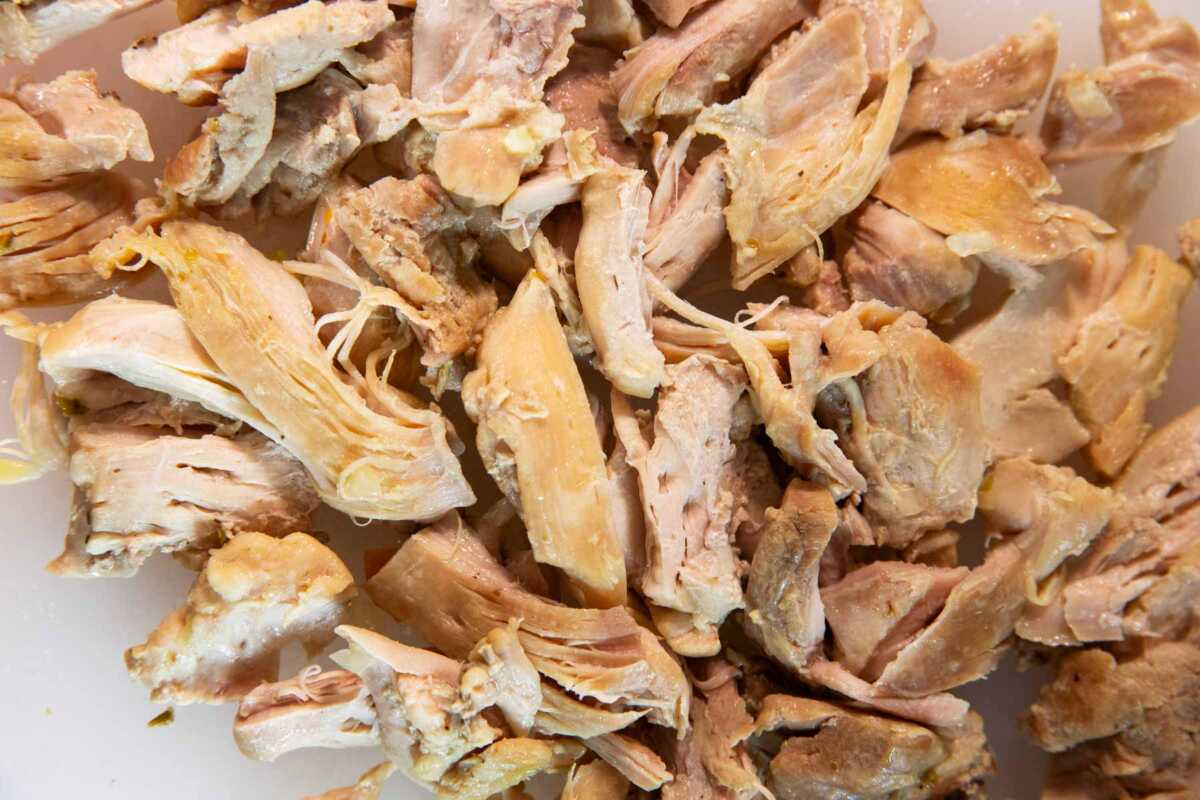Shredded chicken on a plastic cutting board.