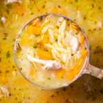 Close up of a ladle with lemon chicken orzo soup.