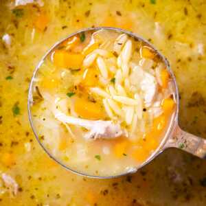 Close up of a ladle with lemon chicken orzo soup.