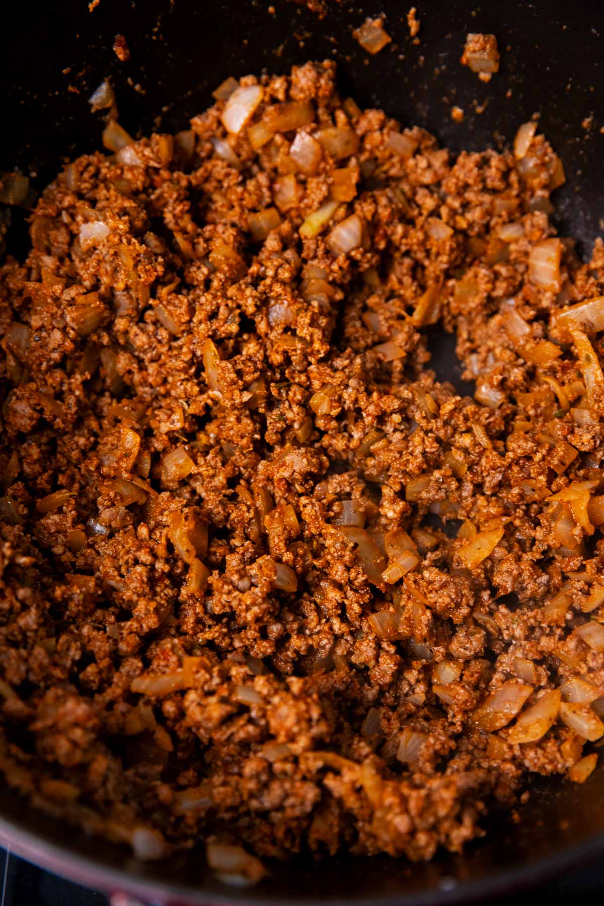 Frontal view of seasoned and browned ground beef in a cast iron pot.