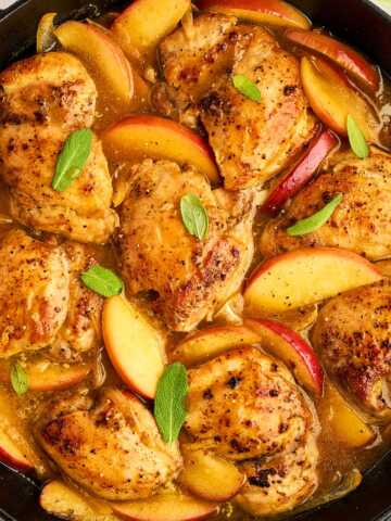 Overhead view of apple chicken in a cast iron skillet.