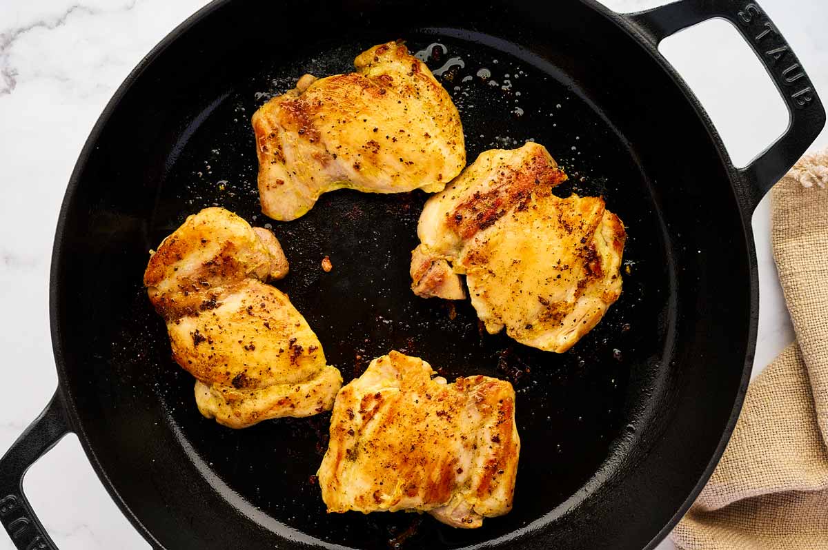 Seared chicken thighs in a cast iron skillet.