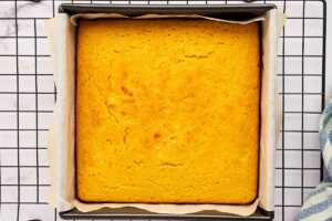 Baked cornbread in a metal pan on a cooling rack.