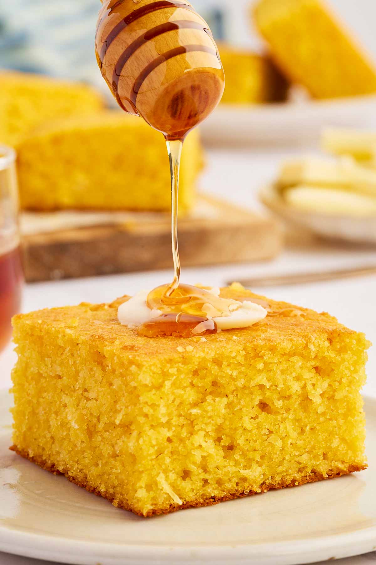 Honey drizzling over cornbread from a wooden honey spoon.