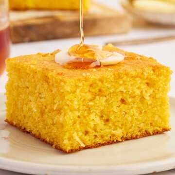 Honey drizzling over cornbread from a wooden honey spoon.