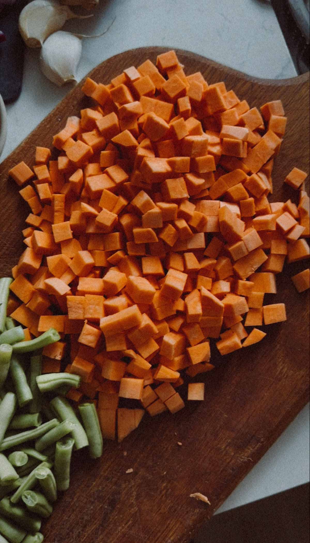Diced sweet potatoes on a wooden cutting board.